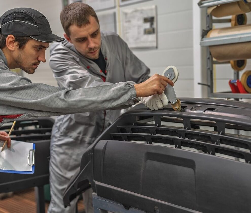 An employee of the paint shop of the automobile plant conducts training on the preparation of bumpers for painting