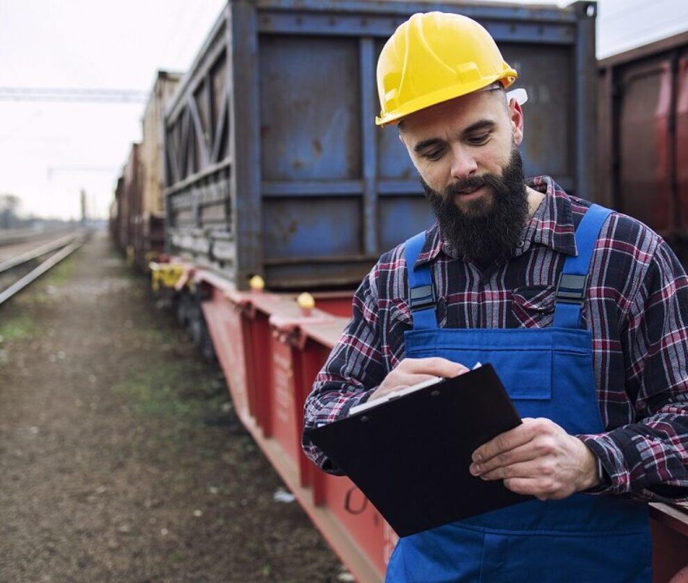 Worker dispatching cargo containers for shipping companies via freight train and organizing goods to be exported.